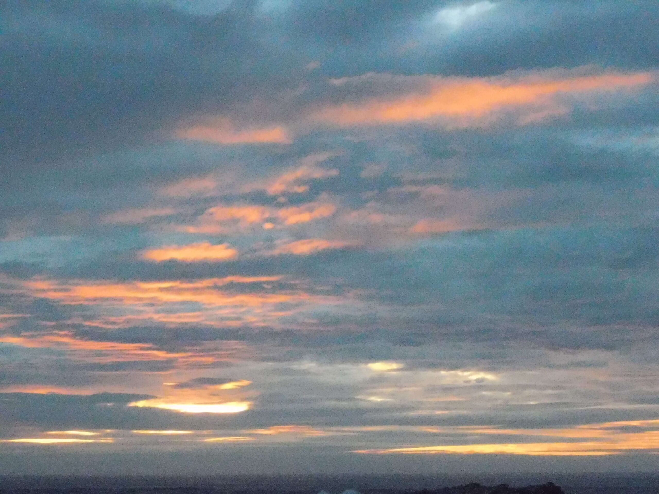a cloudy sunset sky enfiladed with streaks and patches of gold and orange